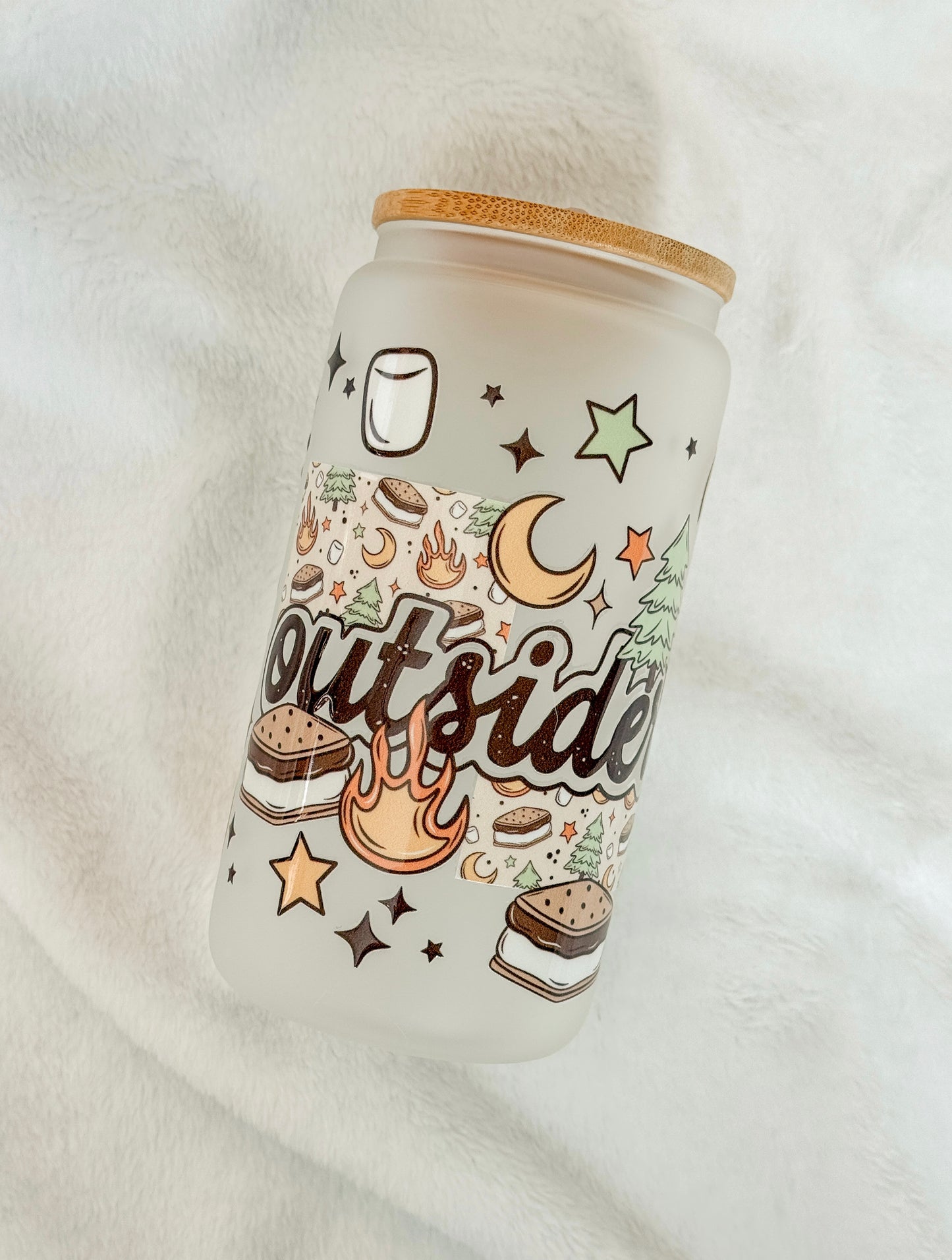 Tumbler with 'outsider' and camping supplies on a white background